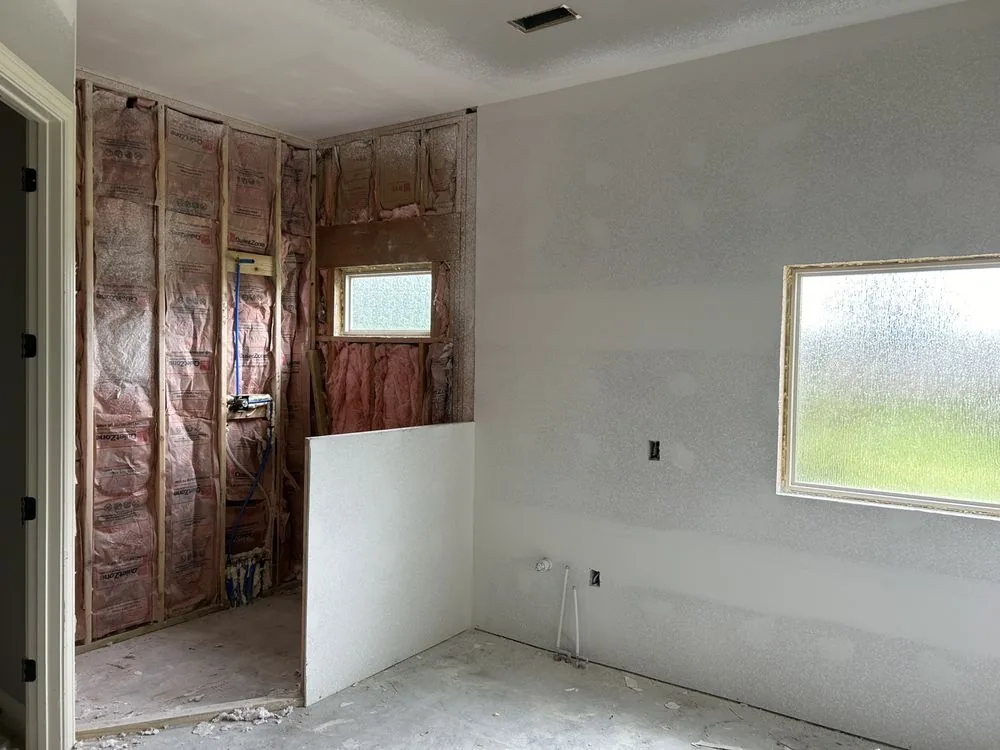 Bathroom remodel with new drywall hung and textured on the ceiling and walls next to an open framed shower area.