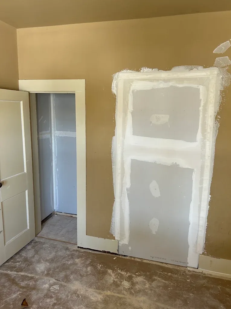 Old doorway opening closed with new taped drywall on a bedroom wall